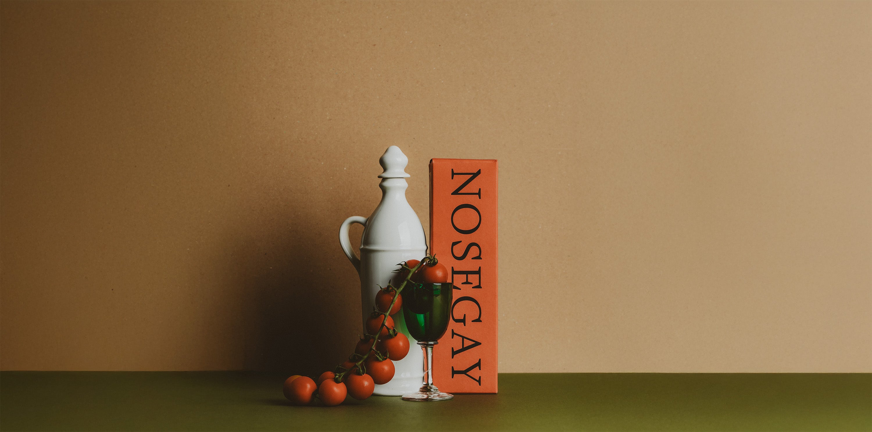 Decorative still life with a white vase, green apple, and orange fruits on a brown background.